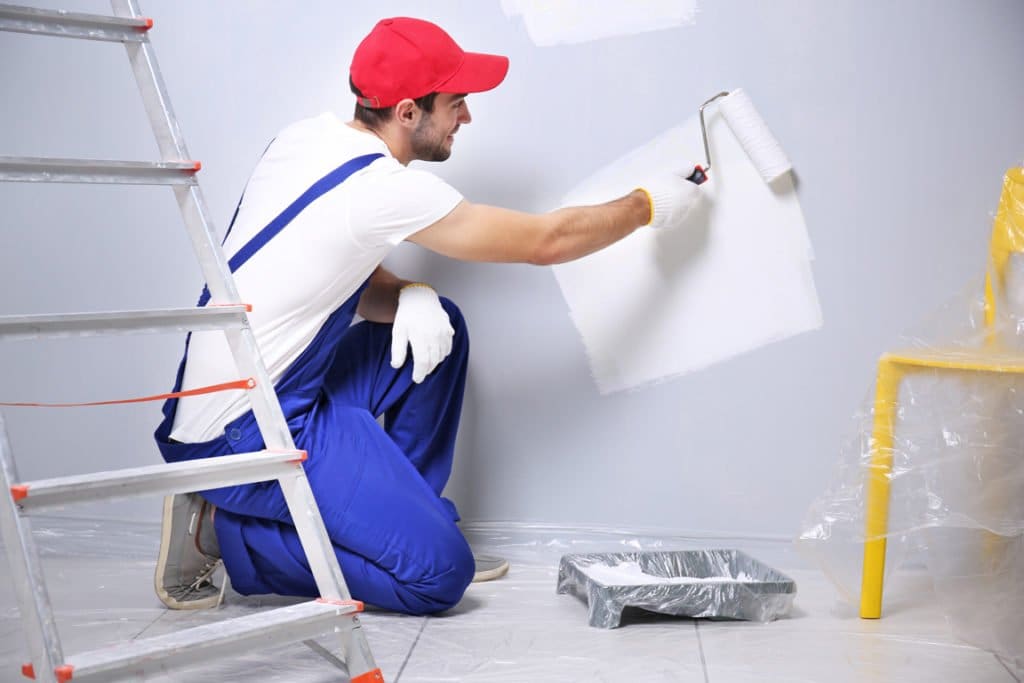 Painter rolling white paint onto an interior wall – selling a painting contractor business in Florida
