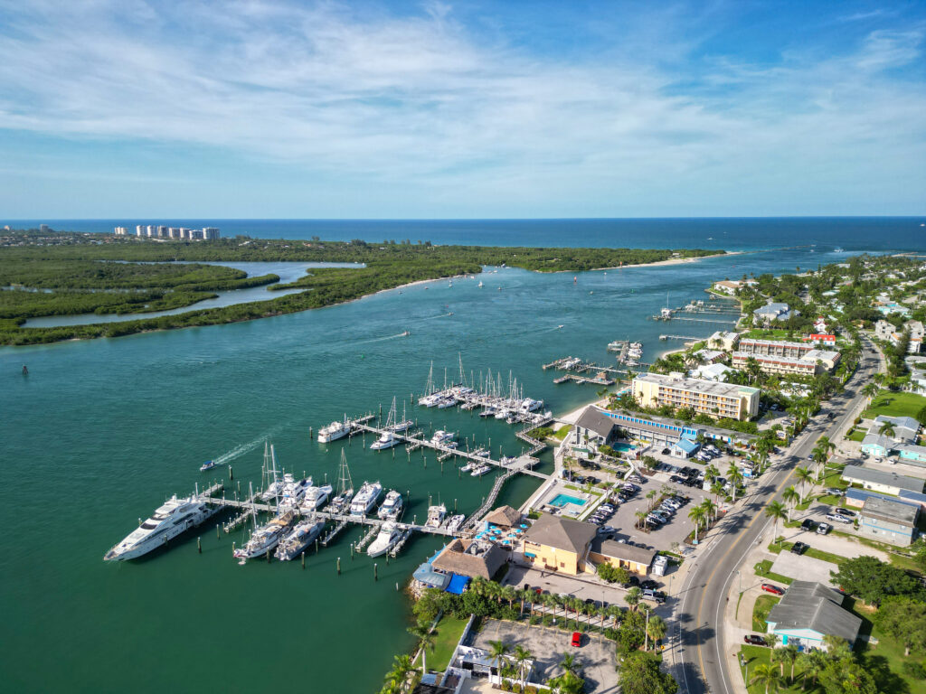 Aerial view of a marina in Port St. Lucie, Florida, showcasing boats docked along the waterfront, lush greenery, and residential buildings, emphasizing the area's appeal for business growth and community development.