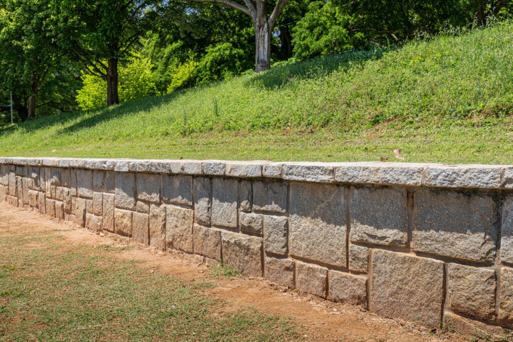 Stone retaining wall supporting a grassy slope – selling a retaining wall contractor business in Florida